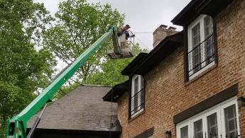 Pressure washing roof of home from cherry picker